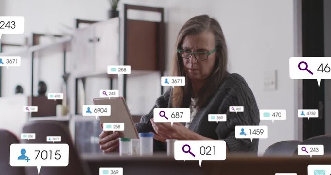 Mature woman tapping tablet comparing greencap bottle, health icons overlaying table, aiding meds