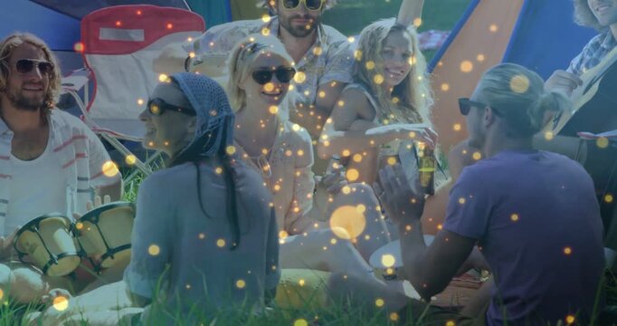 Group on grass tapping bongos starting guitar strumming for music, golden bokeh overlaying group
