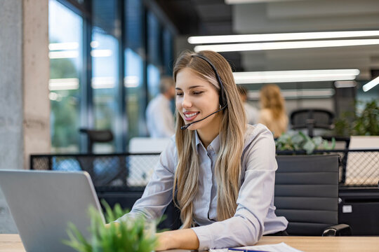 Portrait of happy smiling female customer support phone operator at workplace.