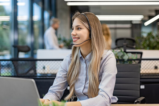 Portrait of happy smiling female customer support phone operator at workplace.