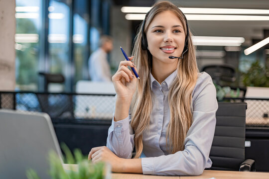 Portrait of happy smiling female customer support phone operator at workplace.