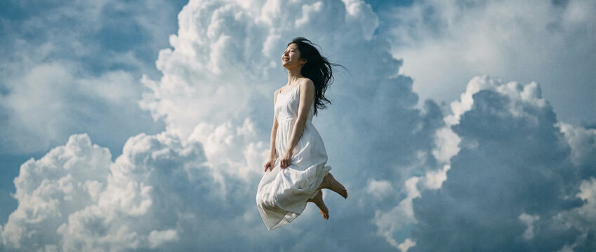 Joyful woman jumps high smiling in front of dramatic cloudy sky cinematic