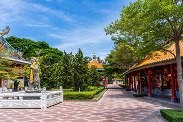 Obraz premium Colorful Chinese temple roofs and garden path surrounded by greenery at Suphan Buri shrine