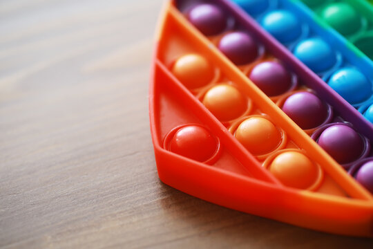 Colorful Rainbow Pop It Fidget Toy on Wooden Table - Sensory Stress Relief and Fun