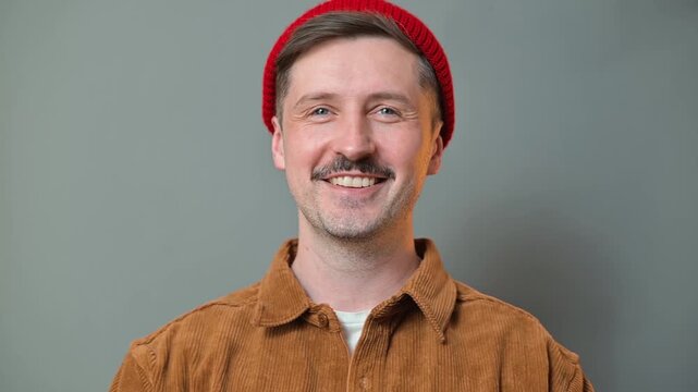 A man poses in multiple angles wearing a red beanie and brown jacket. His expressions change subtly as he looks towards the camera, creating versatile content suitable for diverse projects