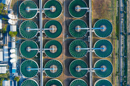 Drone wide angle shot of modern water treatment facility with multiple sedimentation tanks and large water reservoirs, illustrating environmental engineering and sustainable water infrastructure.