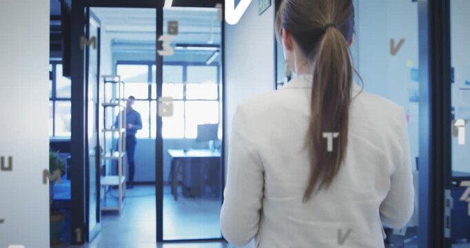 Animation of letters, numbers over rear view of woman using digital tablet while walking in corridor