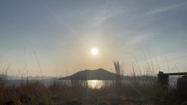 A calm coastal scene in the Seto Inland Sea, Japan. Gentle waves move quietly under soft natural light, with a peaceful island landscape in the distance. The atmosphere is still and minimal, capturing