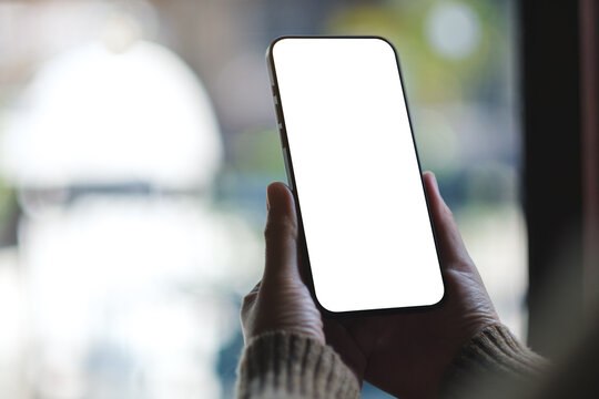 Mockup image of a woman holding and using mobile phone with blank desktop screen