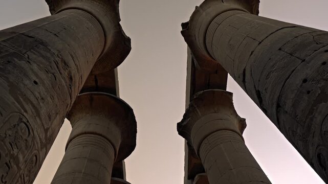 This clip captures the Great Colonnade at Luxor Temple in Luxor, Egypt, during the final moments of sunset. The camera moves beneath two rows of seven soaring columns, each reaching 16 meters height.