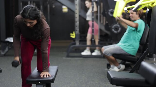 Sportive Latina girl working out with dumbbell in well-equipped gym during weight training session . High quality 4k footage