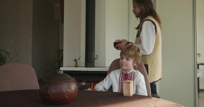 Kid Boy Waiting For Dinner. Man Serving Dishes on Table Family in Ukrainian Traditional Attire Childhood. 4K 10-bit