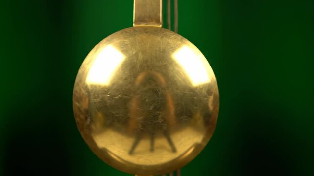 The pendulum of an old grandfather clock swinging slowly and rhythmically, isolated on solid green background professional footage, design element, passing time