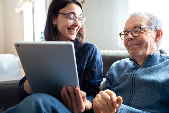 Young woman teaching elderly man using digital tablet