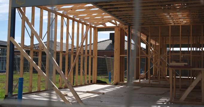 Timber frame of a new residential house under construction in Australia, showing structural beams and open layout before completion. Home building processes, and suburban development in progress.