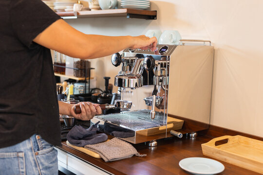 Barista preparing espresso by flushing the group head on espresso machine.