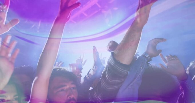 Spotlight intensifying, music fans raising arms at concert while light flares washing over hands