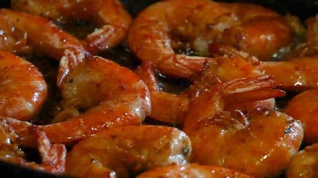 Shrimp frying in a hot pan with oil and seasonings. Fresh seafood cooking process. Delicious meal preparation for healthy dinner at home in a culinary kitchen.