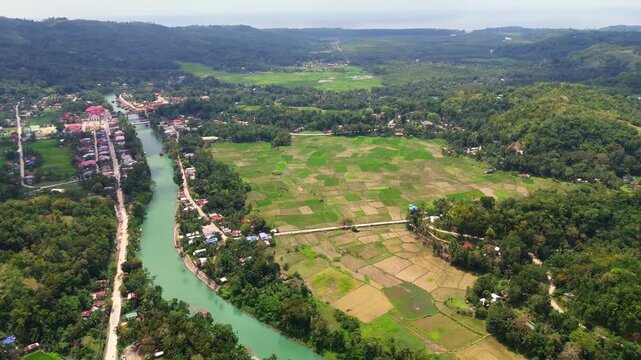 Aerial view of the green Loboc River winding through lush tropical jungles and rice fields in Bohol, Philippines. A iconic natural landmark and major tourist attraction in the Visayas