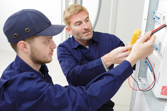 electrician checking voltage of fuse board