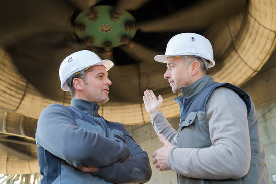 workers stood underneath industrial turbine