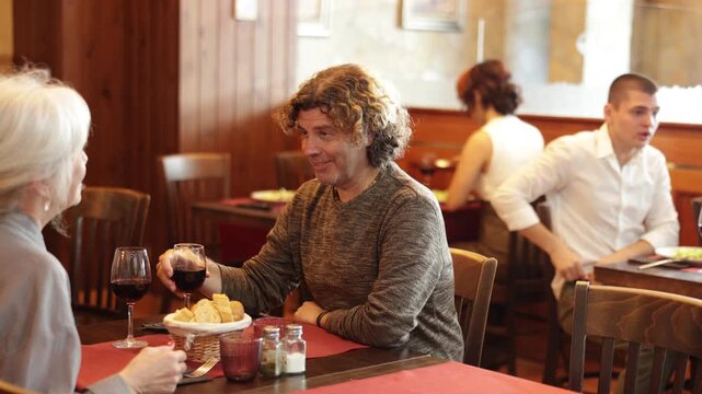 Polite young waitress presents fresh salad plates to adult couple in a cozy restaurant. High quality 4k footage