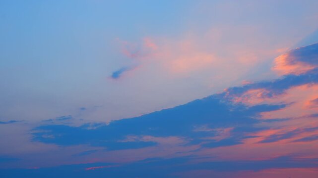 A stunning sunset sky timelapse capturing vibrant orange and pink clouds, with sun rays peeking through, showcasing dramatic cloud textures and the tranquil beauty of dusk.

