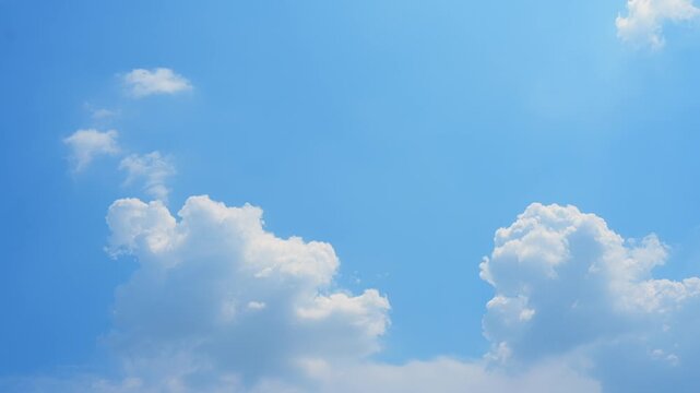 A timelapse of a clear blue sky, capturing fluffy white clouds drifting gracefully across the frame, showcasing dynamic cloud shapes, soft sunlight reflections, and the serene, peaceful beauty day.
