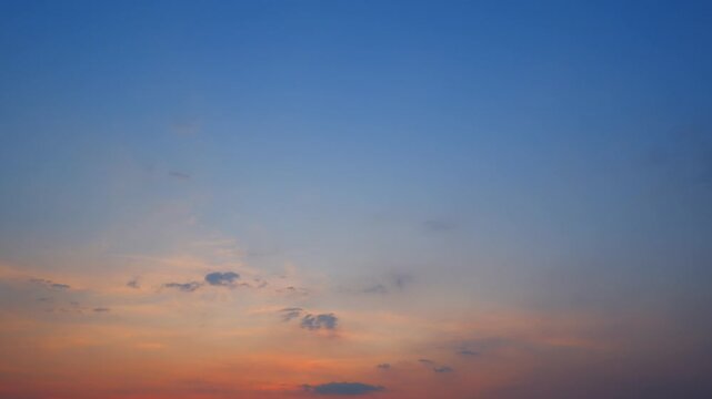 Showcasing altocumulus and scattered stratocumulus clouds drifting across a gradient sky, glowing with orange and pink tones against a deepening blue horizon.
