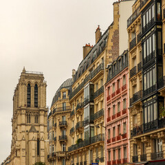 Fototapeta premium Notre Dame Cathedral tower rising above classic Haussmann buildings and Parisian street architecture
