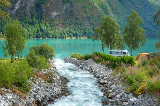 campsite with a camper van and tent by a turquoise fjord in Olden, Norway