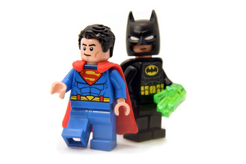 Fototapeta premium Lego minifigures of Superman in costume with red coat and batman in black coat with crystal. Editorial illustrative image of popular children toys and comic heroes.