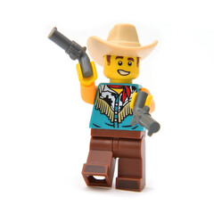 Fototapeta premium Lego minifigure of Cowboy in costume with hat is playing with two guns. Editorial illustrative image of popular children toys.
