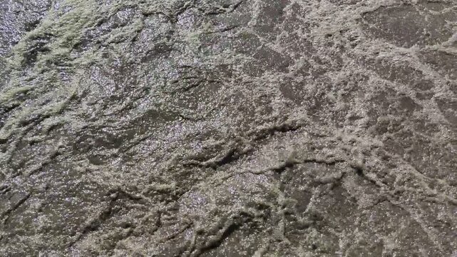 Close-up of the active aeration tank in a wastewater treatment plant. High-angle view of bubbling brown sludge and biological processes used in industrial water purification and treatment.