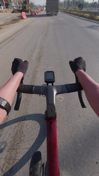 View from cyclist's perspective on an open road, showcasing handlebars and distant traffic under a clear sky.