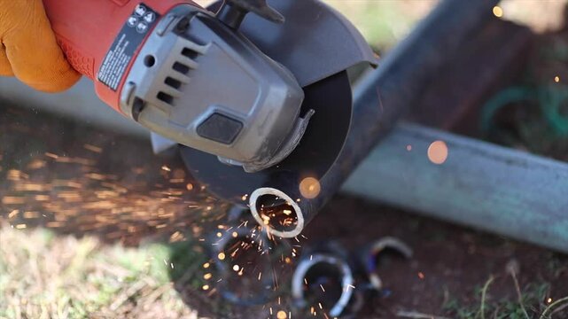 Man is cutting a metal list by angle grinder saw.