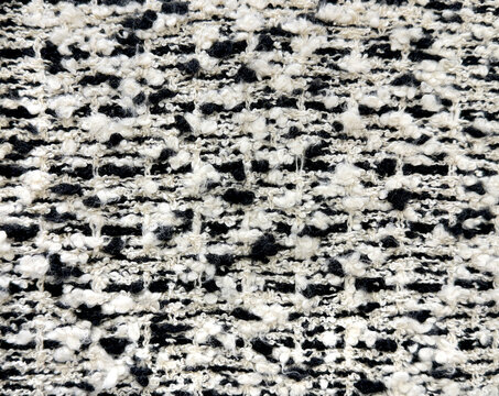 Close up texture of black and white boucle fabric. Curled and nubby knitted tufted texture. Suitable for sofa, upholstery, curtain, and drapery. Seamless background fabric texture.