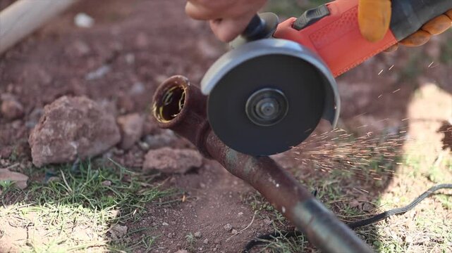 Man is cutting a metal list by angle grinder saw.