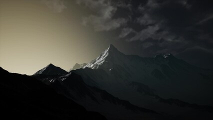 A towering mountain peak stands tall against a darkening sky, illuminated by the warm hues of the setting sun. Shadows dance across the surrounding rugged terrain, creating a dramatic contrast. © icetray