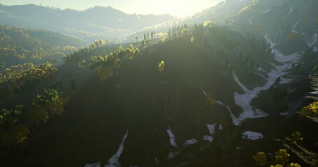 Gentle sunlight cascades over rugged mountains, highlighting lush greenery and patches of snow. Nature awakens as morning light bathes the landscape in a warm glow, creating tranquility. © icetray