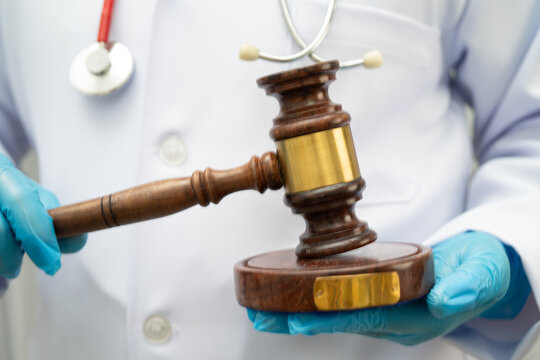 Asian doctor holding court hammer for and crime law justice, forensic medicine.