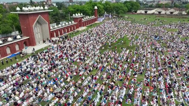Dinajpur, Bangladesh - 21 March 2026: Aerial view of a vast gathering praying in unison at Ghor Shahid Boro Maidan, framed by the brick mosque's architecture.