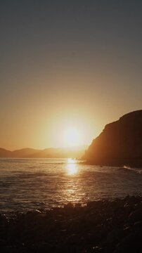 Golden sunset over sea and pebble beach shoreline