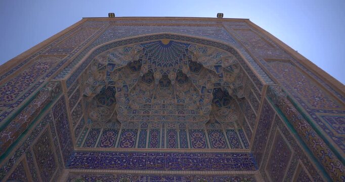 Low angle video of ornate Islamic iwan with intricate mosaic ceiling geometric patterns and tiled facade monumental Central Asian architecture heritage travel landmark Central Asian heritage