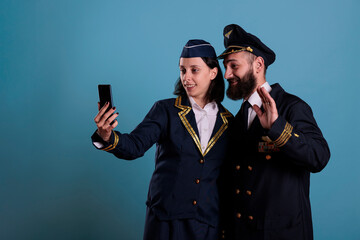 Smiling copilot and air hostess talking on smartphone online videocall together. Airlane captain...
