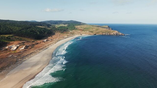 Drone orbit right over Praia do Rostro in Galicia, Spain revealing wide sandy beach and Atlantic waves along rugged coastline.