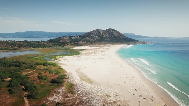 Drone zooming out and rising above Praia de Louro revealing Monte Louro, beach, hills and Atlantic coastline in Galicia, Spain.
