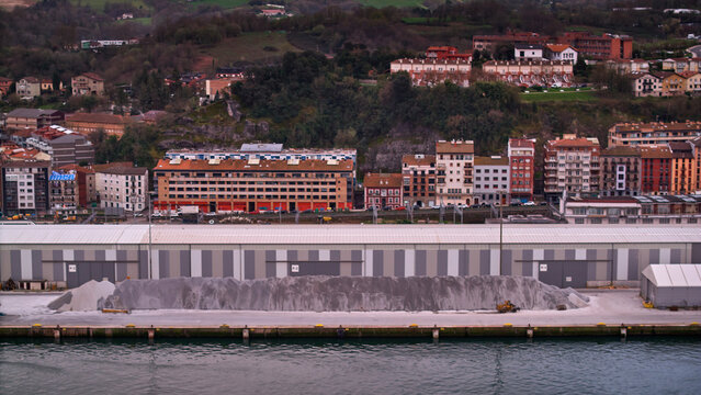 Pasai Donibane, Spain - 10 March 2026: Aerial view of the harbor's industrial area, where the cool gray of the stone blends with the town's warm hues, contrasting with the dark sea.
