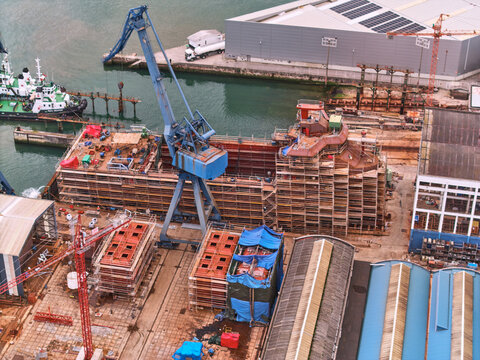 Pasai Donibane, Spain - 10 March 2026: Aerial view of a bustling harbor where colossal ship sections rise under the watchful eye of towering cranes.