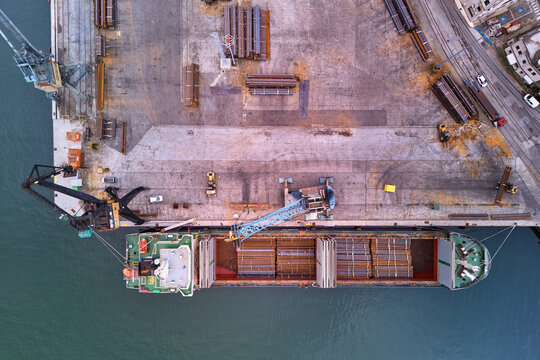 Pasai Donibane, Spain - 10 March 2026: Aerial view of a cargo ship docked at the harbor, contrasting the industrial steel against the calm, reflective water.